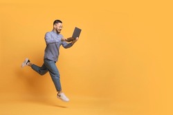 Online Sales. Excited Young Asian Man With Laptop Computer Running Over Yellow Background, Happy Millennial Male Looking At Screen And Smiling, Enjoying Website Offer, Full Length, Copy Space