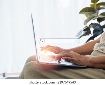 Online Searching Concept. Empty Blank Search Bar With Magnifying Glass Icon Appear While Hands Of Senior Woman Using Laptop Computer. Elderly Female With Internet. Older People And Technology.