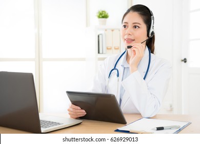 online service female doctor provide the most appropriate medical information for calling patient with laptop computer and mobile digital tablet pad record talking content.