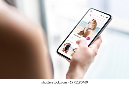 Online Shop Website In Phone. Fashion Store Product Page In Smartphone. Woman Looking For Swimsuit Sale. Web Site Mockup. Ecommerce And Retail Business Concept. Customer Buying And Ordering Apparel.