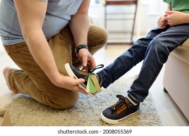Online shopping for baby and kids. Father helping fitting shoes for his child at home. Free of charge courier delivery from online store of children's goods. Fitting and purchase returns.