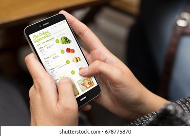 online shopping concept: girl using a digital generated phone with online supermarket on the screen. All screen graphics are made up. - Shutterstock ID 678775870