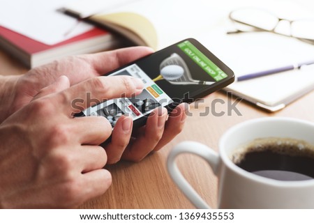 Online shopping concept. Golf shop website on smartphone display.
Closeup of male hands touching smartphone screen at table. 
