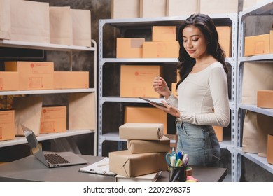 Online Shopping Concept, Happy Young Asian Business Owner Woman Prepare Parcel Box And Check Orders Of Product For Deliver To Customer On Laptop Computer At Home, E-business Marketing On Cyberspace