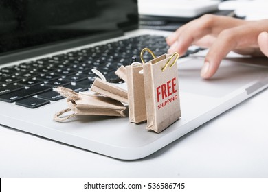 Online Shopping Concept. Miniature Of Reusable Grocery Bags With FREE SHIPPING Text On It And Finger Clicking The Mouse Pad.