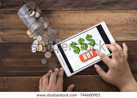 online shopping concept - woman using digital tablet to shop online with coins and wooden background