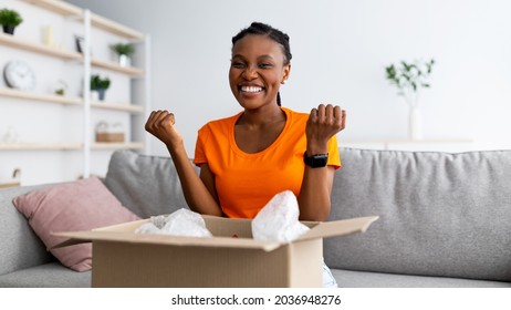 Online Shopping And Delivery Banner. Excited Black Woman Opening Parcel At Home, Making YES Gesture, Satisfied With Her Ordered Product. Joyful Female Customer Receiving Desired Package, Panorama