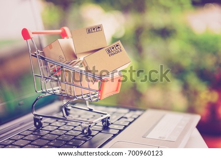 Online shopping and delivery service concept. Paper cartons in a shopping cart on a laptop keyboard, this image implies online shopping that customer order things from retailer sites via the internet.