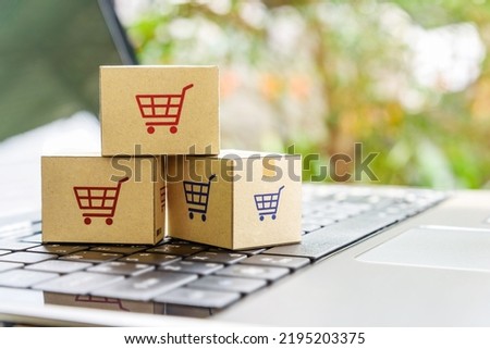 Online shopping, e-commerce concept : Boxes with a shopping cart logo on a laptop keyboard. Shopping service via the internet online website. Home shopping from a retailer includes home delivery.