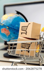 Online Shopping And Ecommerce Concept. Globe And Supermarket Shopping Cart With Boxes On A Laptop Background. Vertical Image