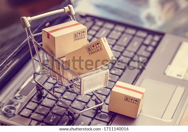 Online shopping  e-commerce and customer\
experience concept : Boxes with shopping cart on a laptop computer\
keyboard, depicts consumers  buyers buy or purchase goods and\
service from home or\
office