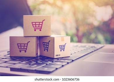 Online shopping / ecommerce and delivery service concept : Paper cartons with a shopping cart or trolley logo on a laptop keyboard, depicts customers order things from retailer sites via the internet. - Shutterstock ID 1023606736