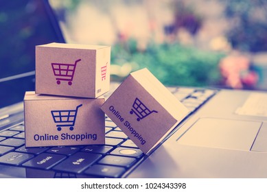 Online shopping / ecommerce and delivery service concept : Paper cartons with a shopping cart or trolley logo on a laptop keyboard, depicts customers order things from retailer sites via the internet. - Shutterstock ID 1024343398