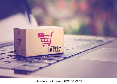 Online shopping / ecommerce and delivery service concept : Paper cartons with a shopping cart or trolley logo on a laptop keyboard, depicts customers order things from retailer sites via the internet. - Shutterstock ID 1024345273