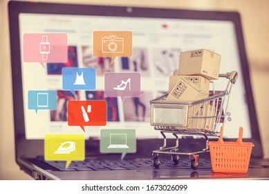 Online Shopping, E-commerce Experience Concept : Box / Carton With Shopping Cart, A Grocery Basket On A Laptop Keyboard, Depicts Consumers / Customers / Buyer Buy Goods And Service From Office Or Home