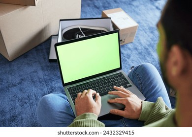 Online shopping, man with laptop, green screen and boxes on floor, shoes and delivery service on digital app. Sale, discount and ecommerce on fashion retail brand website, internet search on computer - Powered by Shutterstock