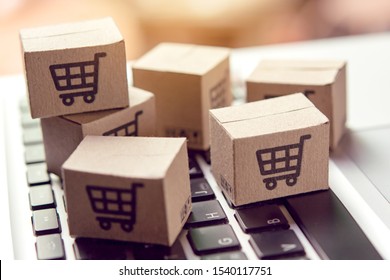 Online shopping - Paper cartons or parcel with a shopping cart logo on a laptop keyboard. Shopping service on The online web and offers home delivery.