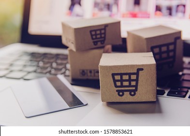 Online shopping - Paper cartons or parcel with a shopping cart logo and credit card on a laptop keyboard. Shopping service on The online web and offers home delivery.