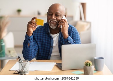 Online Shopping. Senior African American Man Using Credit Card And Laptop, Talking On Phone Calling To Bank For Payment Verification Sitting At Workplace Indoors. E-Commerce And Internet Banking - Powered by Shutterstock