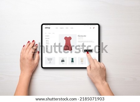 Online shopping with a tablet. Red women's dress on the e-commerce web page