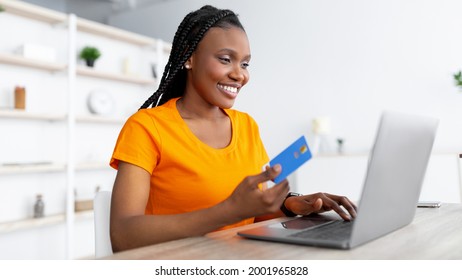 Online Shopping. Young Black Lady With Laptop And Credit Card Sitting At Table Indoors, Purchasing Goods In Web Store, Panorama. Happy Woman Buying Things On Internet, Using Contactless Payment