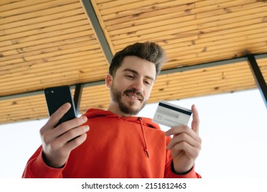 Online Shopping, Young Man Holding Phone And Bank Card Reading Card Information, Online And Easy Shopping, Shipping And Delivery