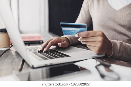 Online-Shopping. Junge Frau, die eine Kreditkarte hält und zu Hause einen Laptop benutzt. Afroamerikanisches Mädchen, das im Café an Computern arbeitet. Business, E-Commerce, Internet Banking, Finanzwesen, Freiberufler-Konzept