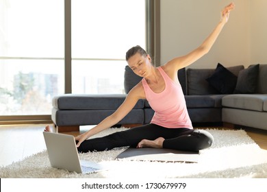 Online Sport Fitness Yoga Training Workout. Young Woman And Doing Exercises On Yoga Mat Opposite Laptop At Home