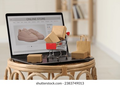 Online store. Laptop, mini shopping cart and purchases on table - Powered by Shutterstock