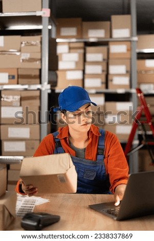 Online store manager using laptop, preparing a parcel for postage. Small Business Owner working in storeroom, Preparing order for buyer. Copy space