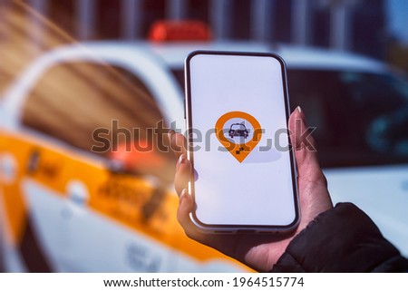 Online taxi in a smartphone. The girl holds the phone in her hands with a mobile application on the screen against the background of the car