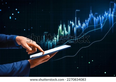 Online trading, investing and stock market concept with man finger on digital tablet touch screen and glowing rising financial chart candlestick and diagram on dark technological background