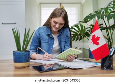 Online training, female teenager sitting at home looking at webcam, Canadian flag on table - Shutterstock ID 2034543368