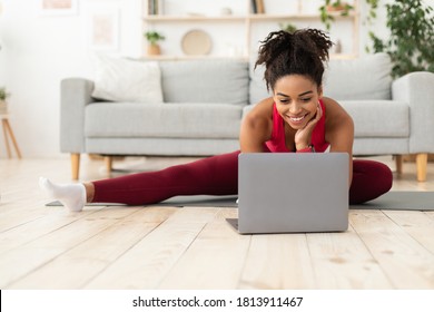 Online Training. Fit Black Woman Exercising Stretching At Laptop Computer Watching Fitness Video At Home