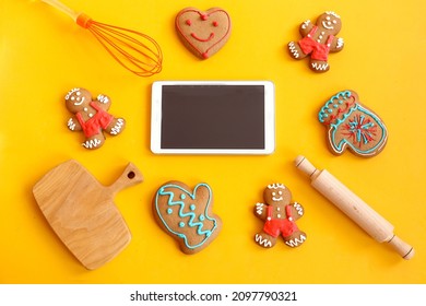 Online Training On Baking Gingerbread: Phone, Gingerbread Men In The Form Of A Mitten, Little Men, Heart, Rolling Pin, Kitchen Wooden Plate On A Yellow Background, Top View