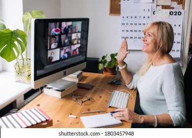 Online-Schulungslehrer. Tag für Tag neue Normalbüro Arbeit von zu Hause. Lächelnde reife Frau mit Videoanruf über Laptop im Studio-Wohnung-Büro. Tägliche Routine. Business-Videokonferenzen. 
