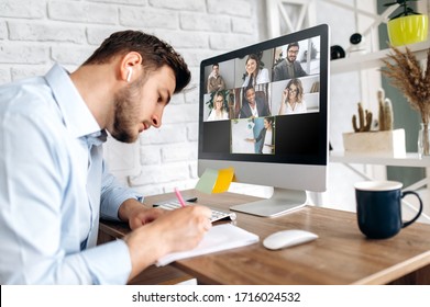 Online training. Young guy learns online by video conference in zoom app. On the screen, the teacher tells the information to him and other participants in the conference - Shutterstock ID 1716024532