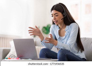 Online Tutoring. Young Asian Female Tutor Having Video Call With Students, Talking At Laptop Camera, Sitting On Couch At Home