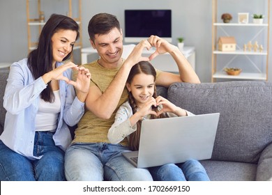 Online Video Chat Online. Family Holds Hands In The Shape Of A Heart Welcomes Waving Friends Using Laptop At Home.
