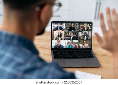 Online video communication concept. Over shoulder view at a laptop screen with different people, employees, business partners, guy greets colleagues, online briefing, brainstorming, group - Shutterstock ID 2188352537