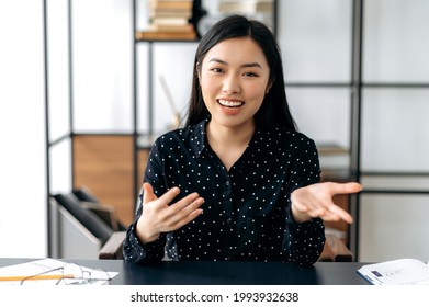 Online Video Communication. Friendly, Pretty, Smart Confident Young Asian Woman, Freelancer Or Manager, Sits At Work Desk, Talking With Colleagues Or Friends Via Video Link, Gesturing Hands, Smiling