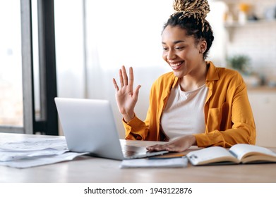 Online video communication. Joyful attractive African American woman, freelancer or student, in casual clothes, uses laptop for online video conference with colleagues or friends, greets, smiles - Shutterstock ID 1943122876