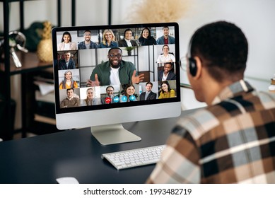 Online Video Communication. Over Shoulder View Of Mixed Race Man, On Computer Screen With Multinational Group Of Successful Business People, Virtual Business Meeting, Telecommunication Concept