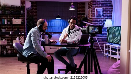 Online vlogger filming podcast episode with man in studio, using camera and soung production equipment to record. Content creator broadcasting live conversation on social media.