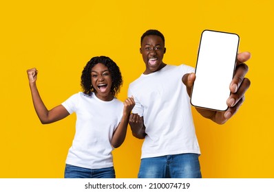 Online Win. Happy Excited Black Couple Holding Big Smartphone With Blank White Screen And Exclaiming With Joy, Collage With Emotional Man And Woman Celebrating Success And Showing Copy Space, Mockup