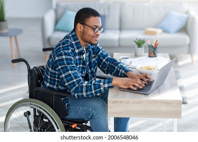 Online Work For Disabled People. Handicapped Black Guy In Wheelchair Using Laptop For Remote Job At Home. Millennial Paraplegic Man Having Business Meeting On Internet, Making Video Call