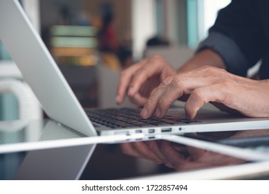 Online working from home, portable office concept. Casual business man, freelancer connecting internet, working on laptop computer with digital tablet on desk at home or coffee shop, close up