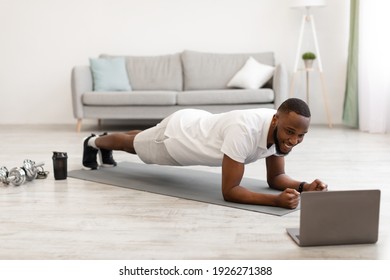 Online Workout. African Guy Exercising At Laptop Standing In Plank Position Training At Home. Modern Sporty Lifestyle, Distant Gym Work Out To Stay Fit During Covid-19 Quarantine Concept - Shutterstock ID 1926271388