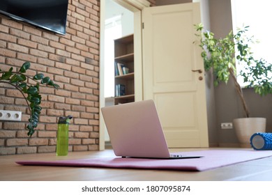 Online workout at home gym concept. Laptop computer on yoga mat on floor in living room in modern apartment interior. Internet fitness training classes remote technology video sport exercises routine - Powered by Shutterstock