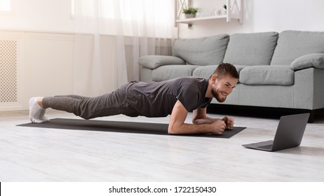 Online Workout. Young Man Doing Plank Exercise With Online Tutorial At Home, Panorama, Free Space
